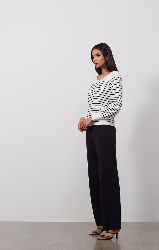 Ecomm photo of a model wearing the Freeport sweater, which is a white knit pullover with black ottoman stripes.