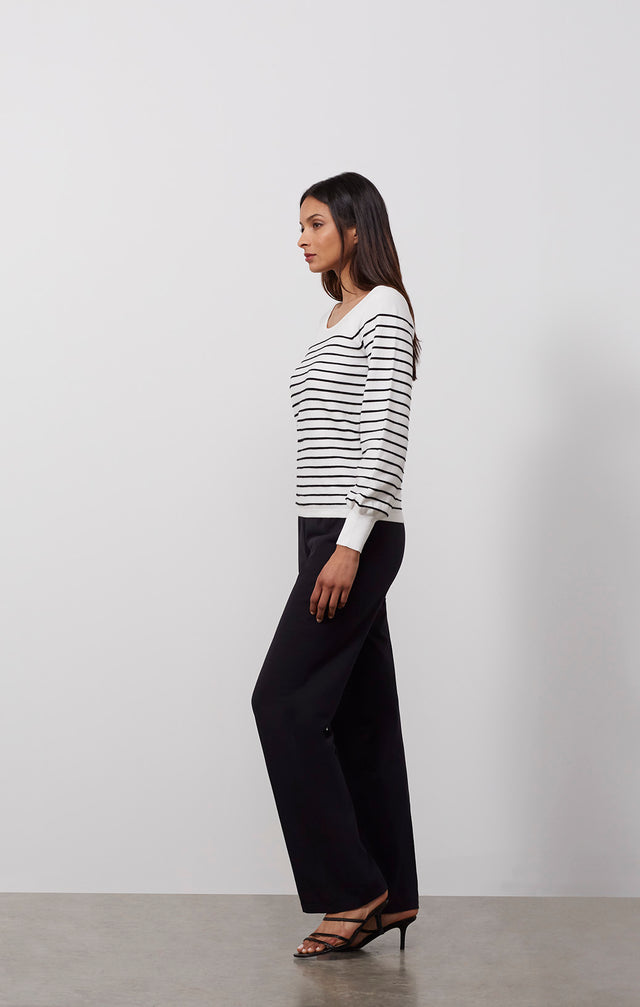 Ecomm photo of a model wearing the Freeport sweater, which is a white knit pullover with black ottoman stripes.