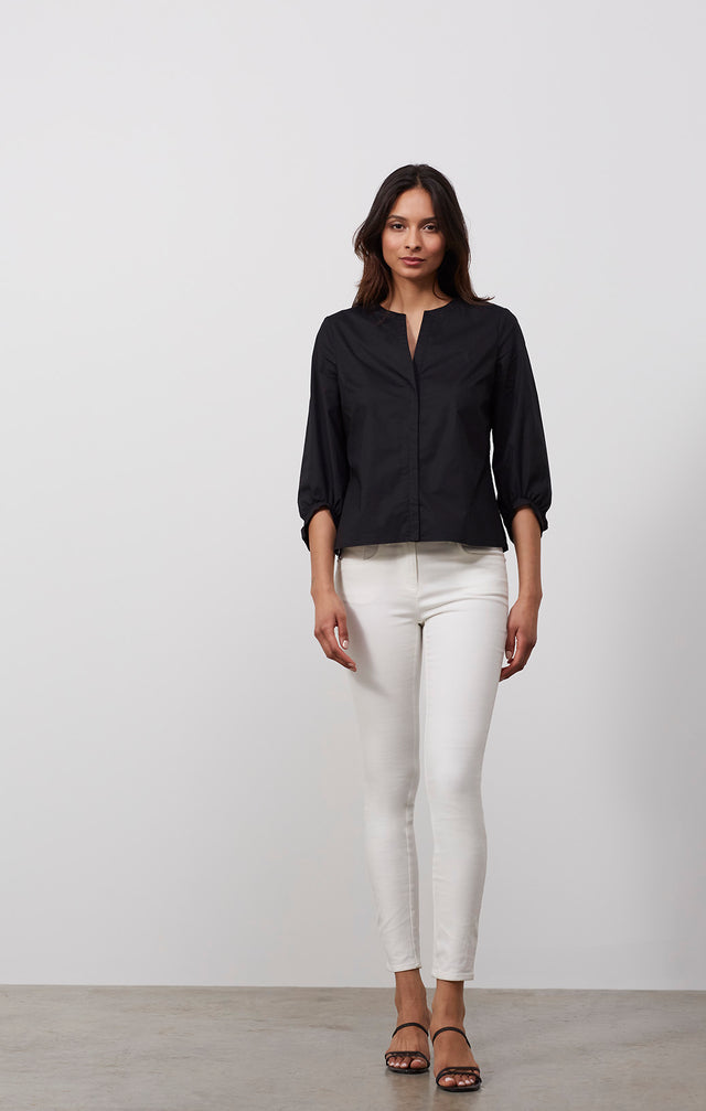 Ecomm photo of a model wearing the Doyenne shirt, which is a stretch cotton black blouse.