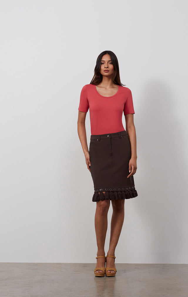 Ecomm photo of a model wearing the Berber skirt, which is a stretch twill jeans skirt with Moroccan tassels.